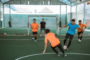 Players in blue uniforms dribble past players in orange uniforms