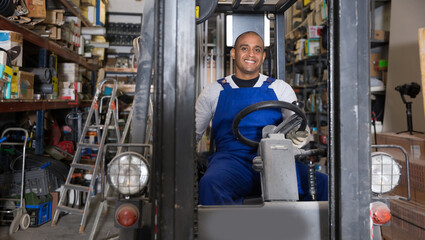Fototapeta na wymiar Foreman drives forklift at the warehouse of a hardware store