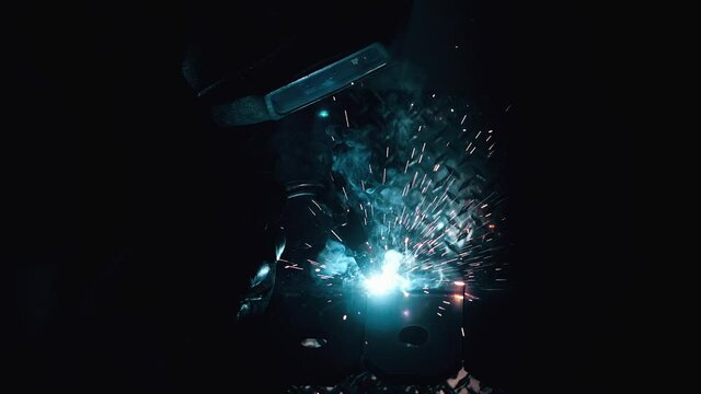 Metal worker welding in dark work shop - high contrast slow motion