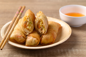 Asian deep fried spring roll filling with tofu, cabbage, carrot and glass noodle on natural plate eating with dipping sauce. Vegan food