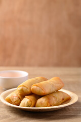 Asian deep fried spring roll filling with tofu, cabbage, carrot and glass noodle on natural plate eating with dipping sauce. Vegan food