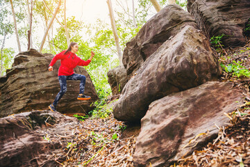 Sport running woman in cross country trail run jumping on the rocky mountain path.	
