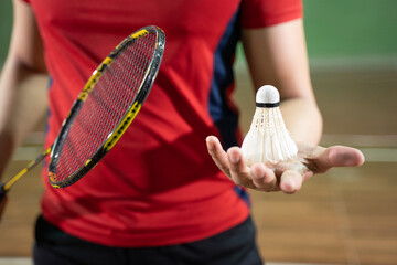 Badminton player in red shirt holding racket and shuttlecock