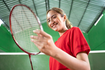Female badminton player holding racket strings to check racket condition