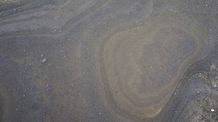Abstract marbleized texture of muddy sand as wallpaper background.