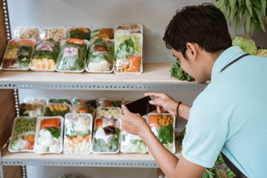 Man using a smartphone to take photos of vegetable products