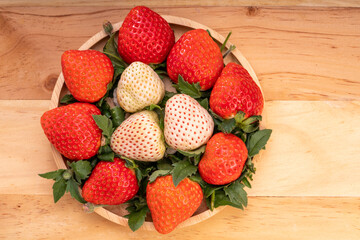 Fresh strawberries in a wooden basket on wooden background, Red Strawberries and white strawberries Pine berry or Hula strawberry in Bamboo basket.