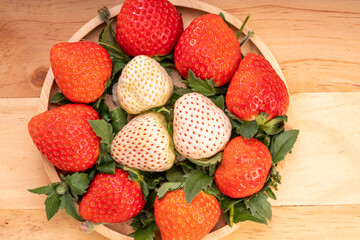 Fresh strawberries in a wooden basket on wooden background, Red Strawberries and white strawberries Pine berry or Hula strawberry in Bamboo basket.