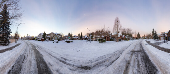 Residential Neighborhood in the Suburbs with White Snow covered road. Sunny Sunrise. Taken in...
