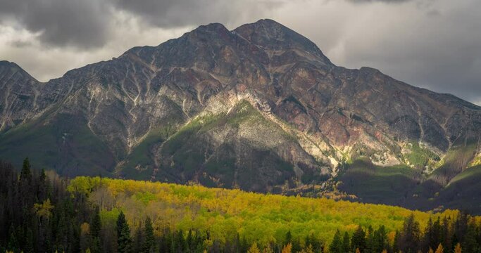 Time lapse, idyllic canadian landscape, clouds and shadows moving above valley with aspen forest and mountain peak on fall day, Jasper National Park