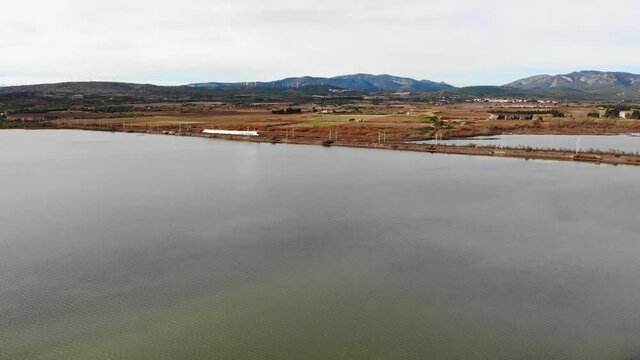 Aerial: passenger train by the sea in southern France during winter. Camera going up