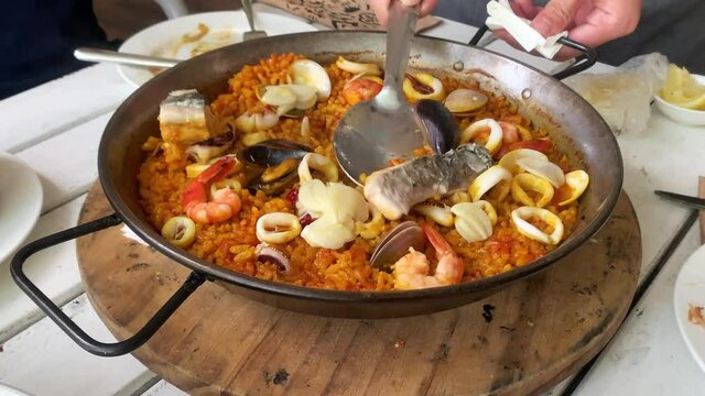 Delicious seafood paella, famous Spanish paella pan dish consists of savory rice dish with clams, mussels, fish, cuttlefish and shrimps