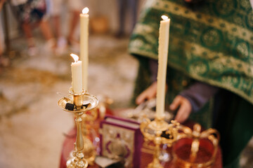 Fototapeta na wymiar Candles are burning on candlesticks in front of the priest in the church