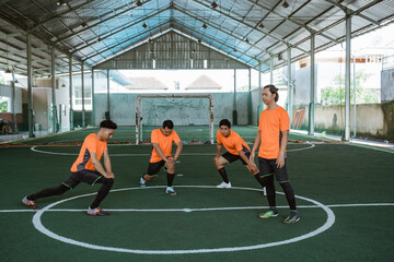some futsal players stretch their legs in the middle court