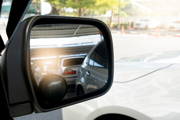 Obraz premium Mirror view of car in parking lot. Blurred image of cars reflected in the mirror in the parking lot. and blurry images with bright lights from outside the car park.