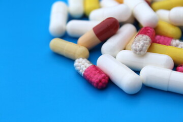A pile of medicines of different sizes and colors lie on a blue background.