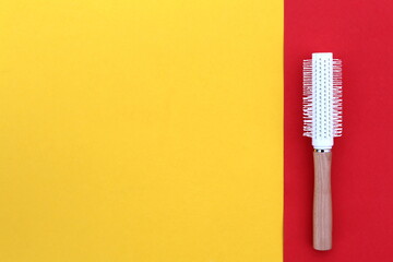 A white hair styling brush lies on a bright background.