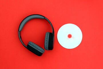 A retro disc with wireless headphones lies on a red background.