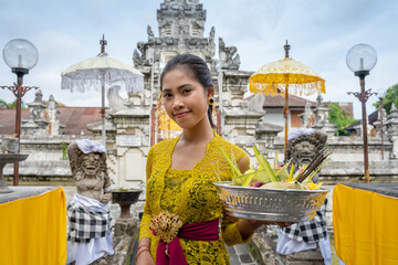 Balinese girl worshipping at a temple - obrazy, fototapety, plakaty