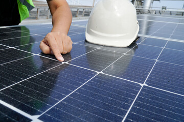 An electrical engineer wearing a white hat is checking. Solar panel cleanliness on the roof of the...
