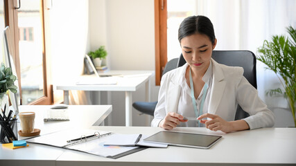 Female entrepreneur holding a credit card at her office space.