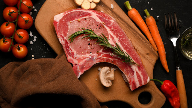 A fresh raw pork chop steak on a wooden board.
