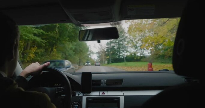 Young Man Drives On a Small Bumpy Road With Yellow and Green Trees Around in Fall, Simrishamn Sweden - Handheld Medium OTS Shot