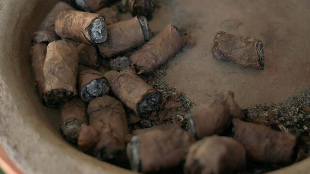 Many cigar butts discarded in ash tray, closeup shot for tobacco industry cancer warning concept.