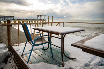 Snow-covered table and chairs at the beach.
