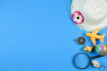 Summer background top view or set of summer accessories on blue background.Hats, airplane, compass, shells, earth and leaves concept for Travel Guide.