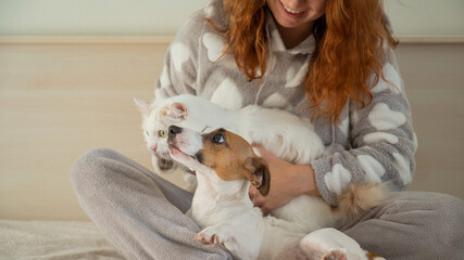 Red-haired Caucasian woman hugging with a dog and a cat.