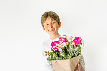 Charming boy with a bouquet of flowers smiles. Greeting card mockup with copy space. Portrait of a boy 8 years old, white, caucasian
