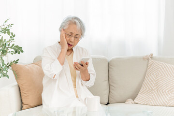 スマホを見る高齢者女性（悩む）
