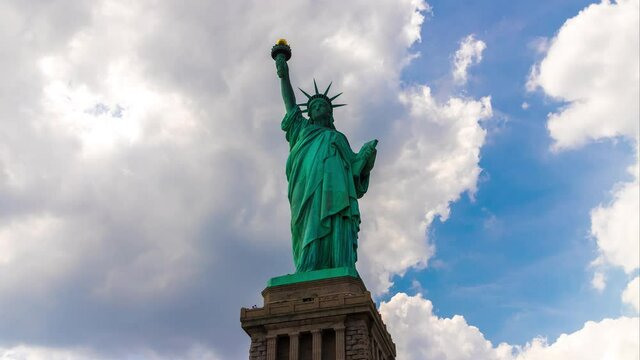 Uhd 4k Timelapse of  Statue of Liberty against blue sky with beautiful cloud background in New York City, NY, USA