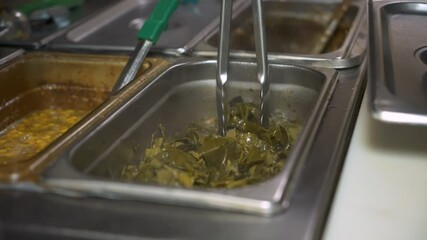 Cook stirs collard greens with tongs, slow motion 4K