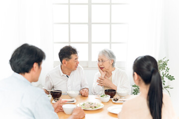 口元をおさえる高齢者女性と家族
