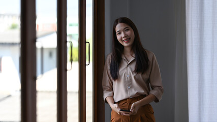 Portrait of confident asian businesswoman standing in office and smiling to camera.