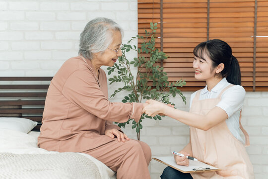 高齢者女性の脈拍を測る介護士の女性