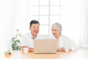 ノートパソコンを見る高齢者夫婦（笑顔）
