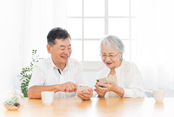 スマホを使う高齢者夫婦（笑顔）
