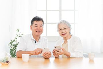 スマホを使う高齢者夫婦（笑顔）

