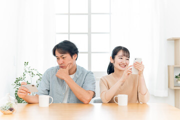 お互いにスマホを見る夫婦（笑顔）
