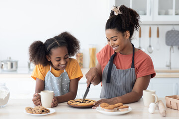 Excited black mom and daughter tasting homemade pie