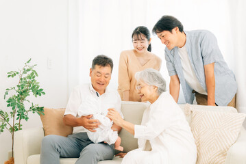 Obraz premium 赤ちゃんを抱いた老夫婦と若い夫婦（里帰り） 
