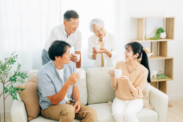 Obraz na płótnie Canvas ソファに座って飲み物を飲む家族（話す） 