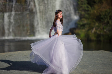 Fototapeta na wymiar a beautiful young girl in a magnificent dress dances against the backdrop of a waterfall, a story about a forest elf