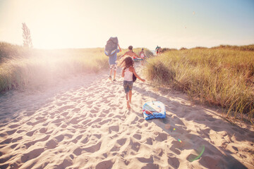 Children carrying body boards up a beachside dune path