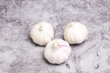 Three heads of garlic on a stone background