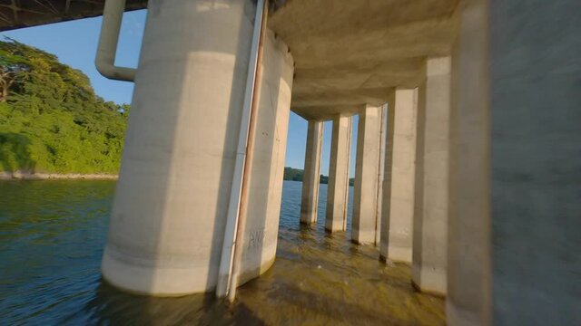 Aerial fpv drone passing through pylons of structure of Hatillo dam pump station, Dominican Republic