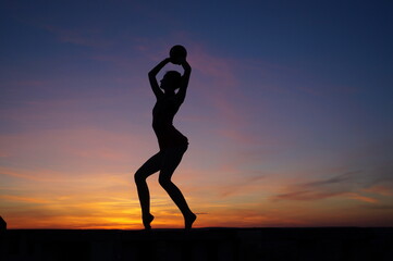 dancer in the dance does the splits in the air against the sunset